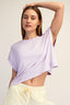 Woman wearing a light purple top and yellow pants against a plain background