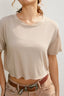 Person wearing a beige t-shirt and light-colored pants with a belt against a plain background