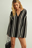 Woman wearing a black and white striped dress against a plain background