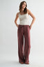 Woman wearing a white tank top and maroon pants on a white background