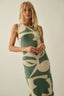 Woman wearing a green and beige patterned dress against a plain background