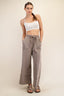 Woman wearing a white sports bra and beige wide-leg pants on a plain background
