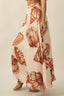 Person wearing a long skirt with shell pattern on a plain background