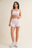 Woman wearing a white patterned sports bra and shorts set on a beige background