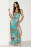 Woman wearing a colorful floral dress with a slit on a white background