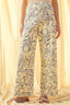 Person wearing floral-patterned pants against a beige curtain background