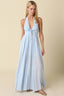 Woman wearing a light blue halter neck dress on a beige background