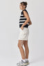 Woman wearing a striped sleeveless top and white shorts on a plain background