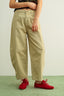 Person wearing beige pants and red shoes on a light green background