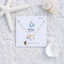 Necklace on a 'Lotus & Luna' card with seashells and starfish on sand