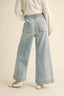 Light blue denim pants worn by a person on a beige background
