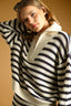 Woman wearing a black and white striped sweater against a beige background