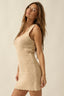 Woman wearing a beige crochet dress against a plain background