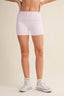 Person wearing white checkered shorts and white high-top sneakers on a beige background