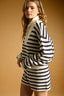 Woman wearing a black and white striped sweater and shorts on a beige background
