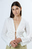 Woman wearing a white lace top against a light background