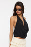 Woman wearing a black halter top and white pants on a white background