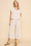 Woman wearing a white top and wide-leg pants on a beige background