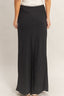 Black pleated skirt worn by a person on a beige background