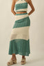 Woman wearing a green and white crochet two-piece outfit on a beige background
