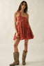 Woman wearing a coral dress with cut-out design and brown cowboy boots on a plain background