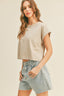 Woman wearing a beige crop top and denim shorts on a plain background
