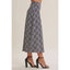 A cropped plaid skirt in navy, white, and gray, shown on a model from the waist down wearing black high-heeled sandals against a solid beige studio background.