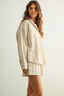 Woman wearing a beige outfit with a plain background