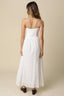 Woman wearing a white dress against a beige background
