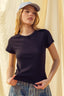 Woman wearing a black ribbed knit top and blue cap against a neutral background