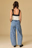 Woman wearing a black top and blue jeans against a beige background