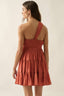 Woman wearing a rust-colored dress with a halter neck on a plain background