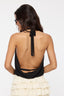 Woman wearing a black halter top with open back and white ruffled skirt on a white background