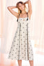 Woman wearing a white dress with black floral patterns against a light background