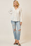 Woman wearing a white button-up shirt and ripped jeans on a plain background