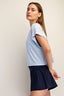Woman wearing a light blue top and navy skirt on a plain background