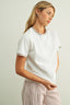 Woman wearing a white t-shirt and checkered pants against a plain background