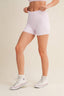 Person wearing light purple checkered shorts with white sneakers on a beige background