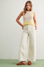 Woman wearing a sleeveless top and wide-leg pants on a plain background