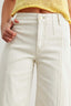 Close-up of light-colored pants with a yellow cropped top on a plain background