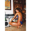 Woman in a red and blue bikini sitting on a kitchen floor with vintage decor.