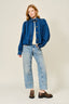 Person wearing a blue denim jacket and jeans on a plain background