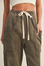 Person wearing olive green cargo pants with a drawstring on a neutral background