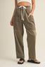 Person wearing olive green cargo pants with a white top on a beige background