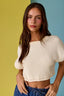 Woman wearing a white ribbed top against a colorful background