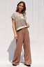 Woman wearing a striped top and wide-leg pants against a white background