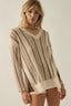 Woman wearing a beige knitted sweater and shorts on a plain background