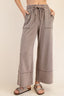 Person wearing brown wide-leg pants with a beige background