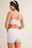 Woman wearing a matching pink and white checkered sports bra and shorts set on a beige background.