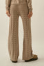 Person wearing a beige knitted sweater and pants on a plain background